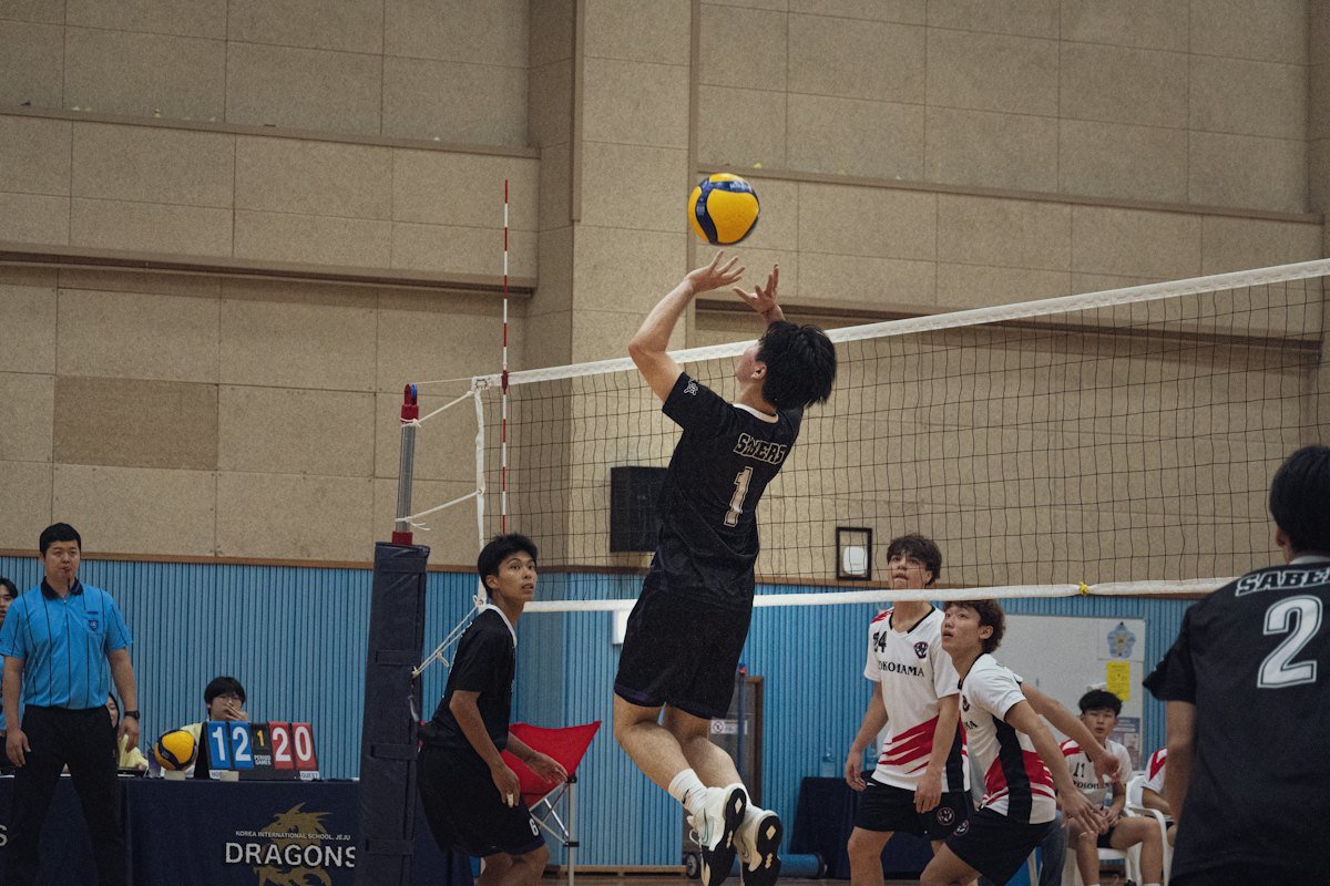 A player jumps to play the ball at the net during an indoor men's match