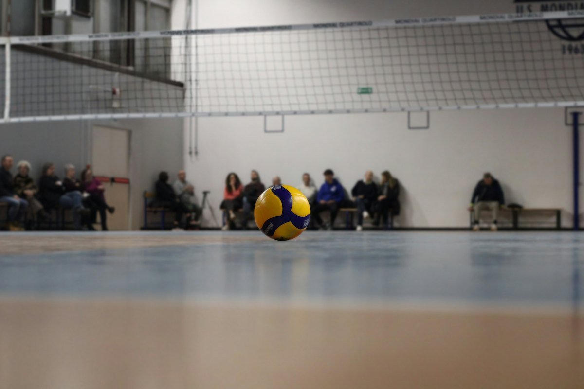 A volleyball on the wooden floor of an empty gym